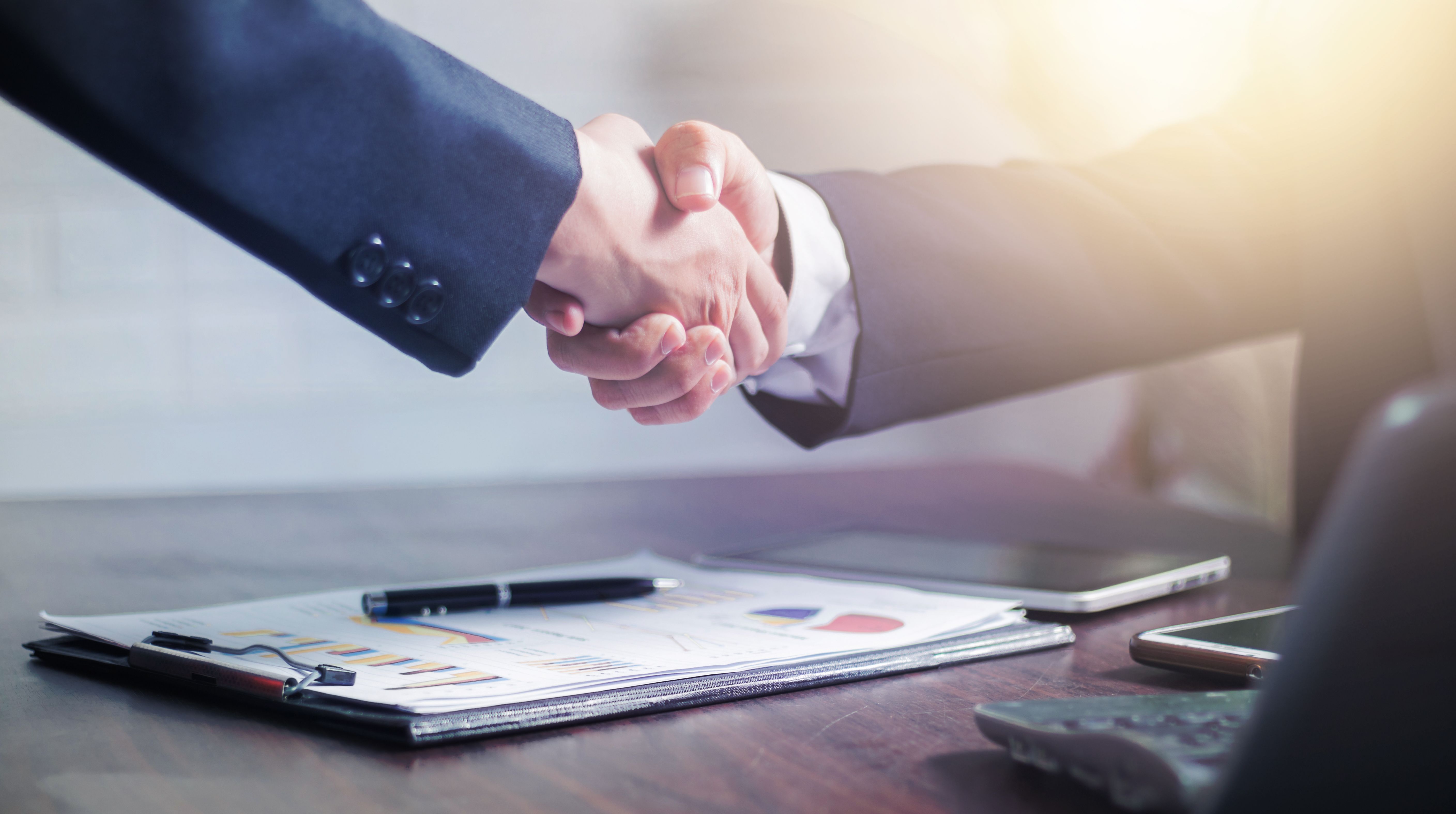 Two people shaking hands after signing an agreement